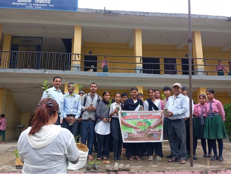 Teachers and eco club members with a plantation banner on the steps of a two storey school
